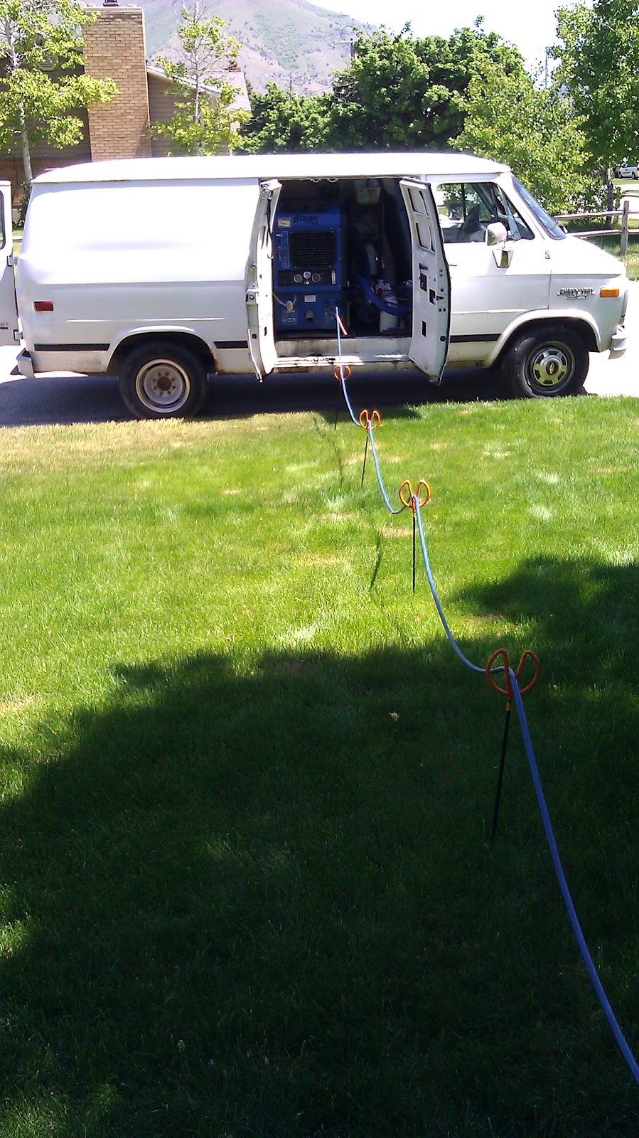 ACDC van in a driveway with the hot rinse hose elevated off the grass
