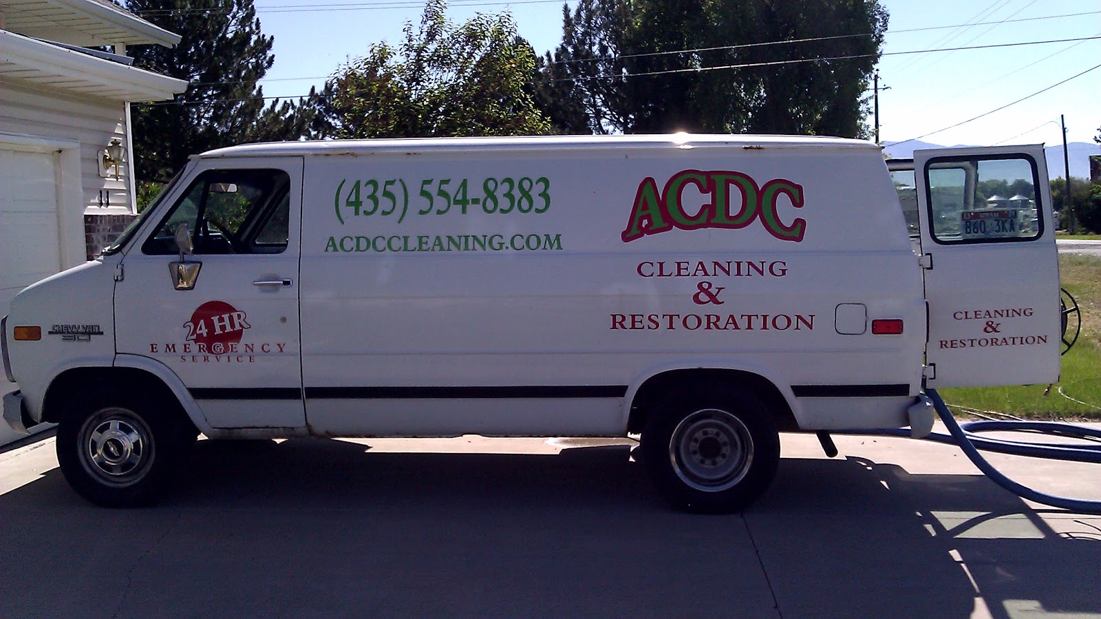 ACDC van in a driveway with hoses running to the house