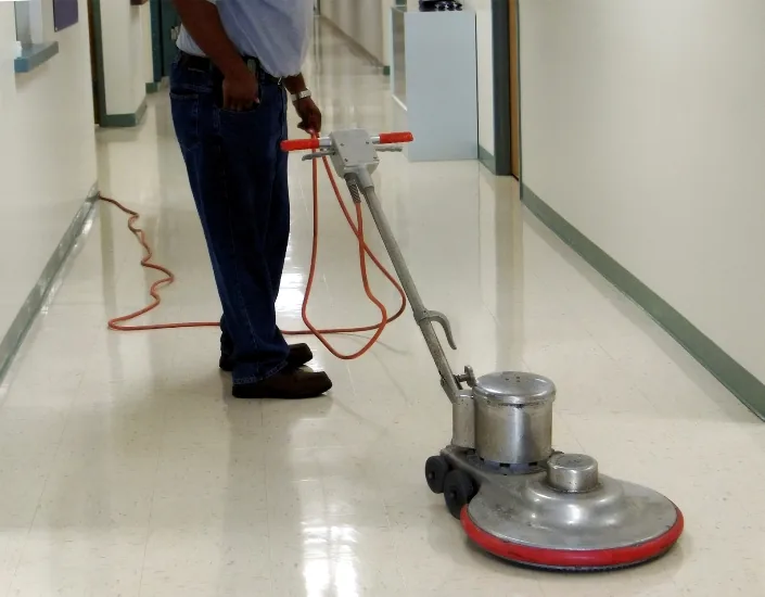 Rotary floor machine on a shiny vinyl tile hallway
